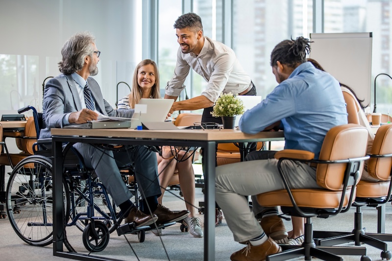 Individuals working in group one in wheelchair with computer