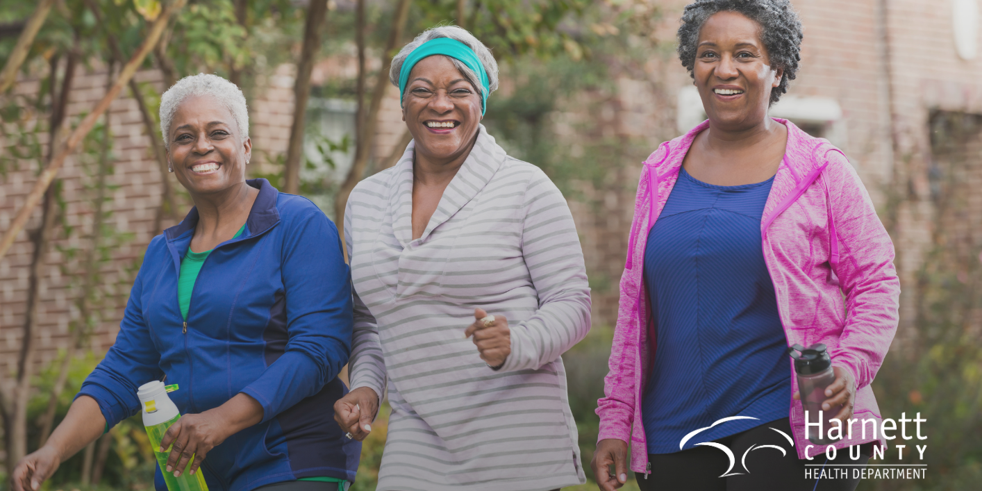 Two African American women smiling while exercising outside in athletic wear.