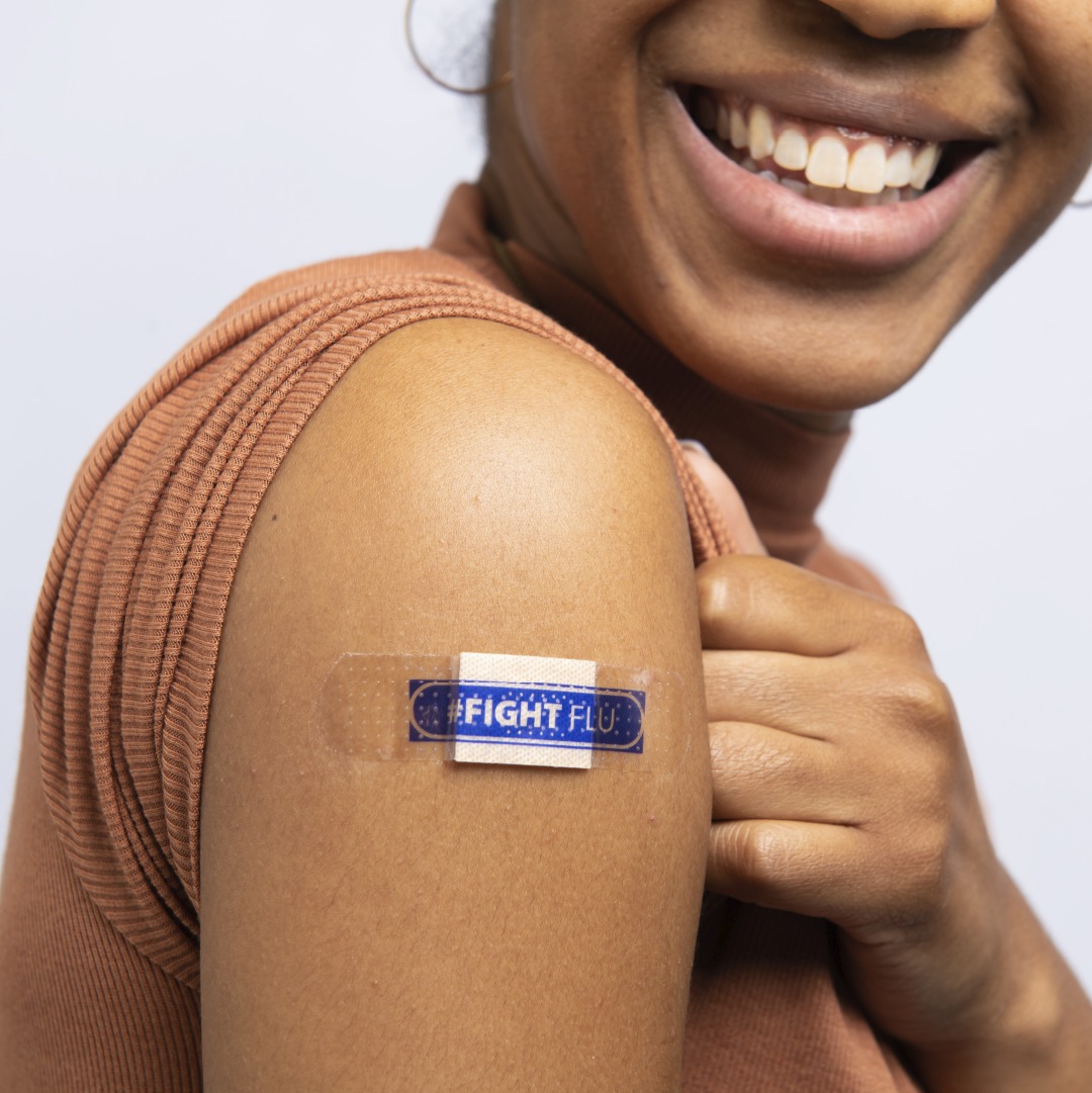 Woman with a band-aid on her arm that says fight flu