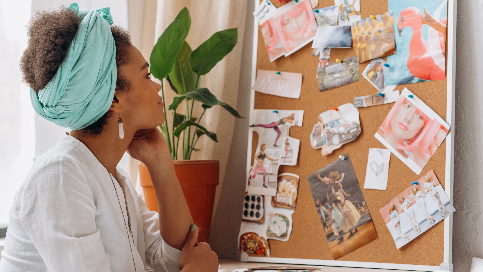 A person looks at a corkboard filled with various inspirational images and photos