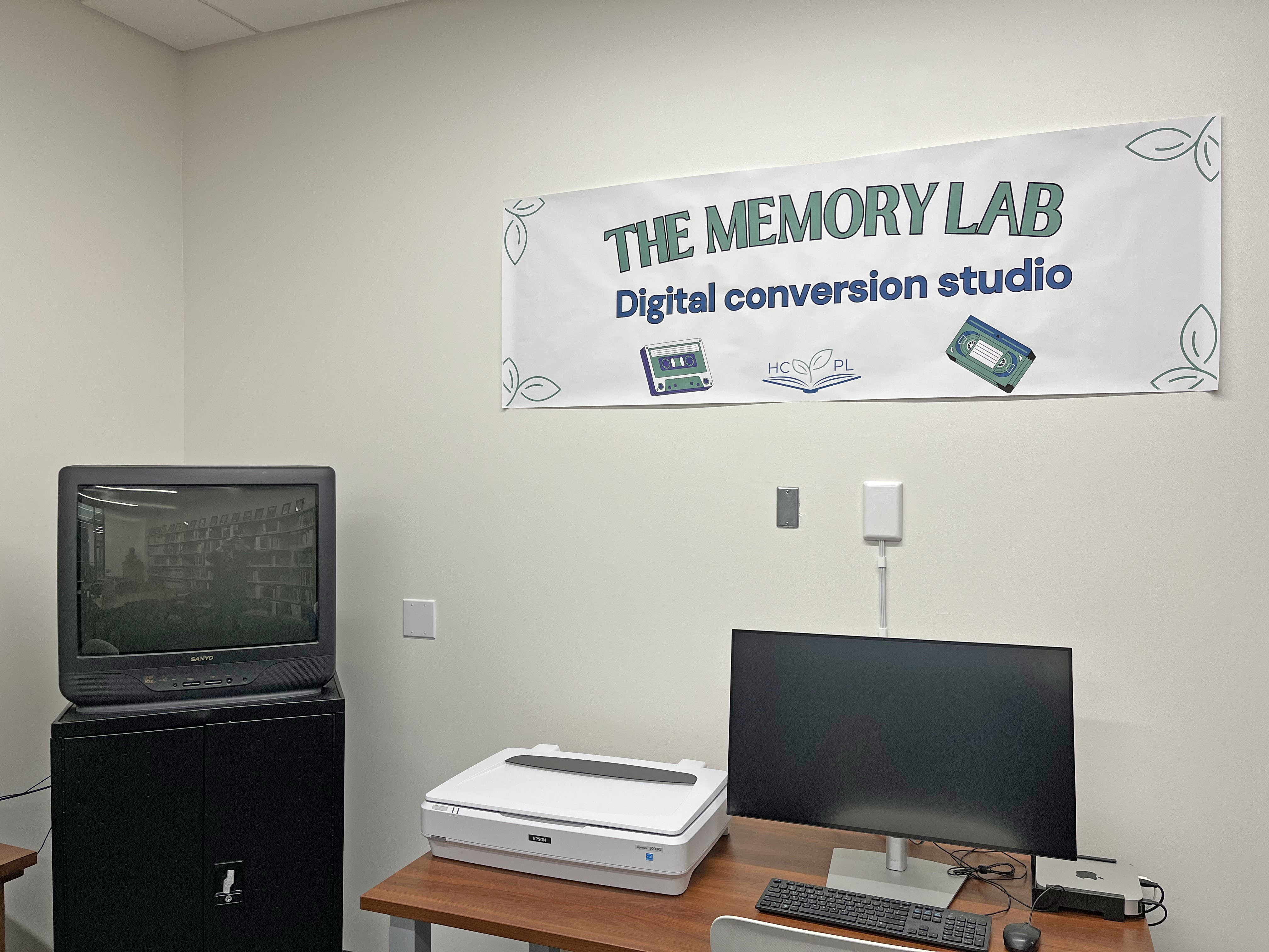 Picture off a room with a computer and equipment. Sign on the wall says Memory Lab